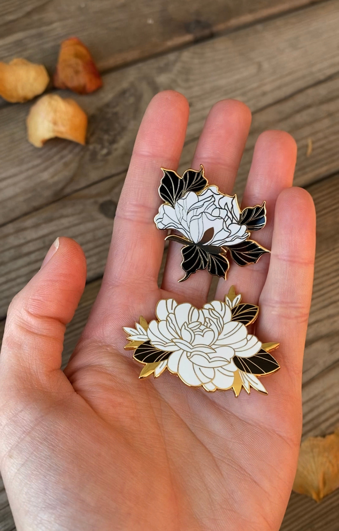 Floral enamel pins on hand, made by Lu Loram-Martin