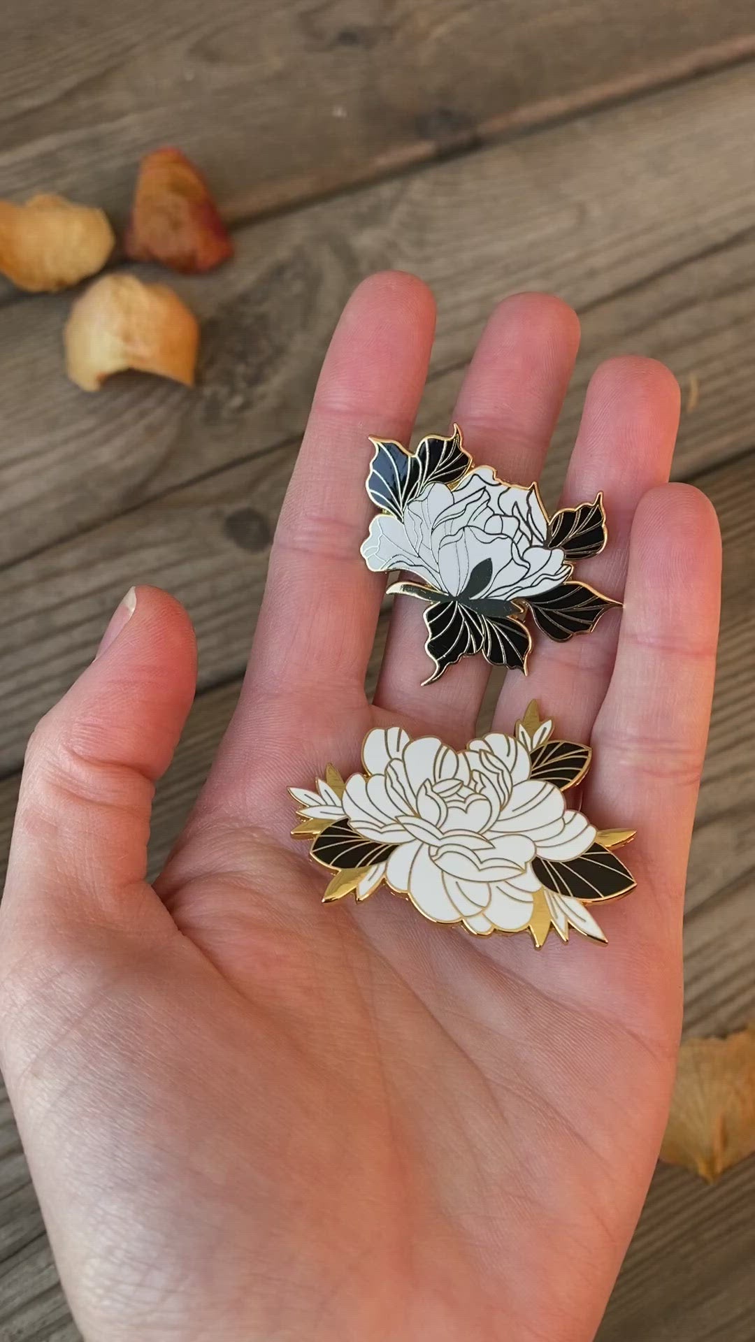 Floral enamel pins on hand, made by Lu Loram-Martin